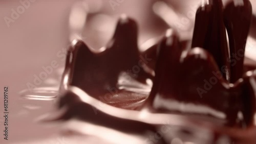 Slow motion video of waves of chocolate splashing and scattering in small drops. photo