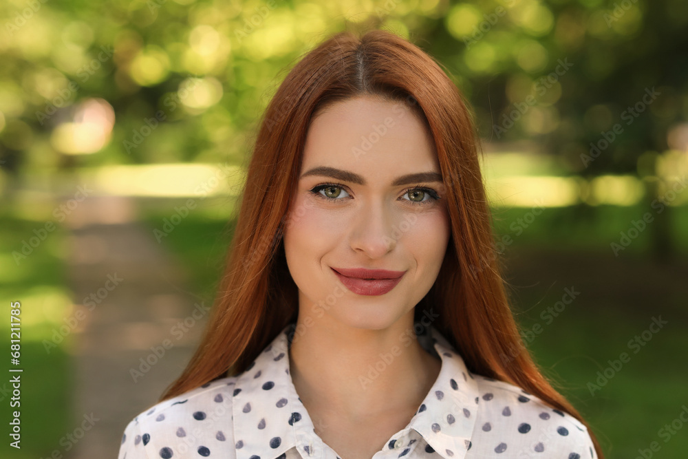 Portrait of beautiful young woman with red hair outdoors. Attractive lady looking into camera Portrait of beautiful young woman with red hair outdoors. Attractive lady looking into camera