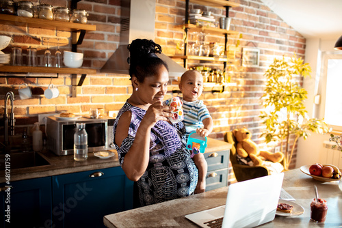 Multitasking African American Mother Working from Home with Baby photo