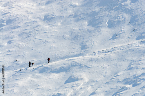 Three tourists on a hiking trail on a snow-covered slope..