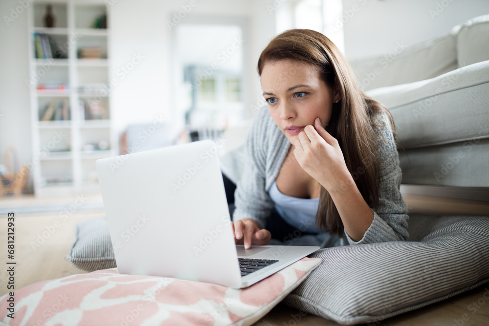 Serious young woman using laptop in living room Serious young woman using laptop in living room