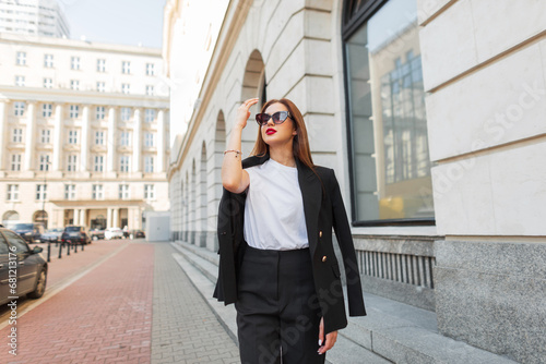 Fashion woman with vintage sunglasses in fashionable clothes with blazer, T-shirt walking on the street