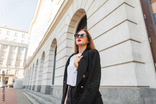 Fashion beautiful urban girl with stylish sunglasses in fashionable casual clothes walks in the city.