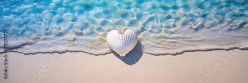 white heart shaped seashell lying in the sand with the blue sea and soft waves in background photo