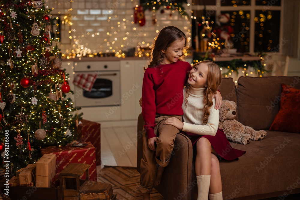 Obraz premium teenage sisters twins at home in the kitchen waiting for the New Year