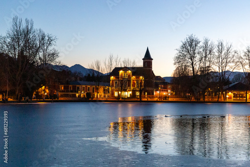frozen lake with a mansion in the background and some birds on the ice. Storybook lake. . Writer