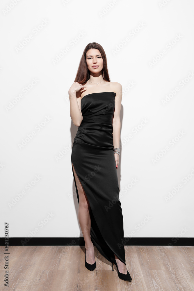 Woman standing confidently in a chic strapless black evening dress, her subtle smile conveying a timeless grace Woman standing confidently in a chic strapless black evening dress, her subtle smile conveying a timeless grace