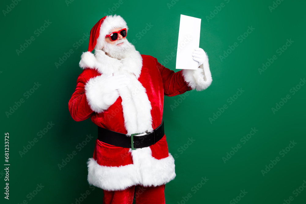 Naklejka premium Photo of cheerful funky claus wear red costume reading obedient children christmas list isolated green color background
