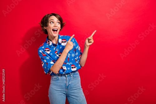 Photo of astonished cheerful person look indicate fingers empty space x-mas ad isolated on bright red color background
