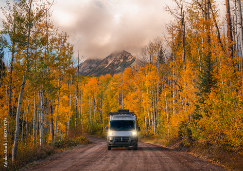 Foto Campervan driving wild forest road with headlights on