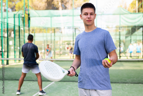 Portrait of cheerful young man padel tennis player in outdoor court. © JackF