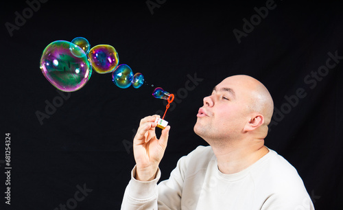 the man blows soap bubbles. black background.