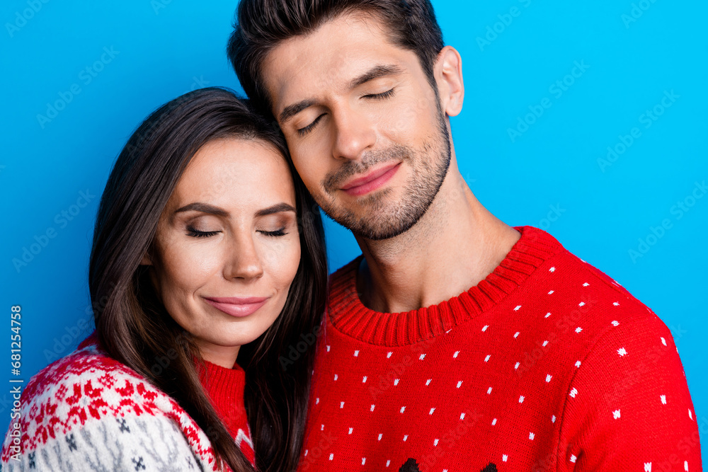 Photo portrait of attractive young couple embrace support each other wear x-mas ornament red sweaters isolated on blue color background Photo portrait of attractive young couple embrace support each other wear x-mas ornament red sweaters isolated on blue color background