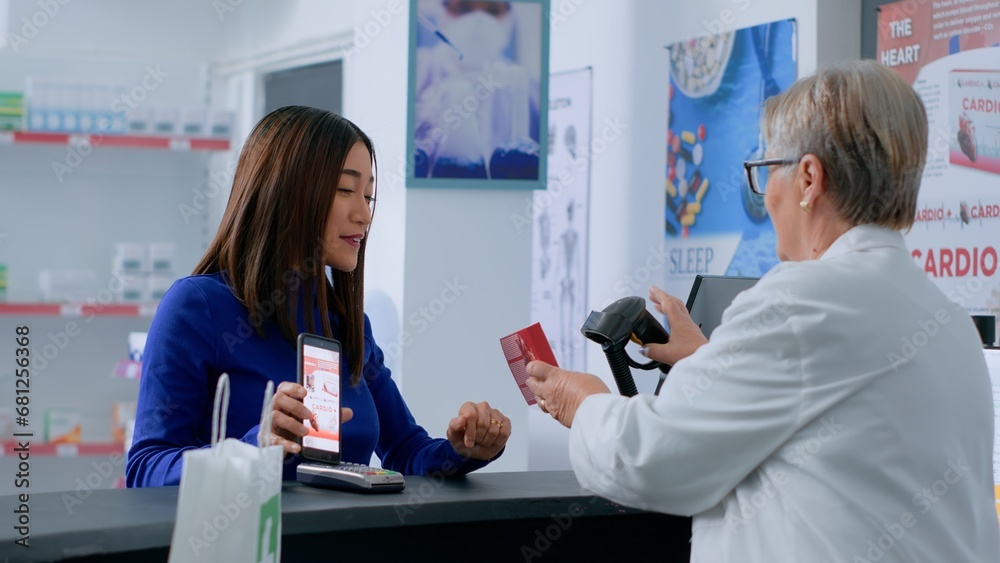Obraz premium Customer at drugstore counter, showing druggist prescribed heartbeat regulating pills picture on smartphone, ready to buy it. Aged wellness specialist selling client required treatment product