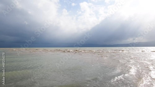 The sun breaks through the clouds and reflects off the waves of the lake