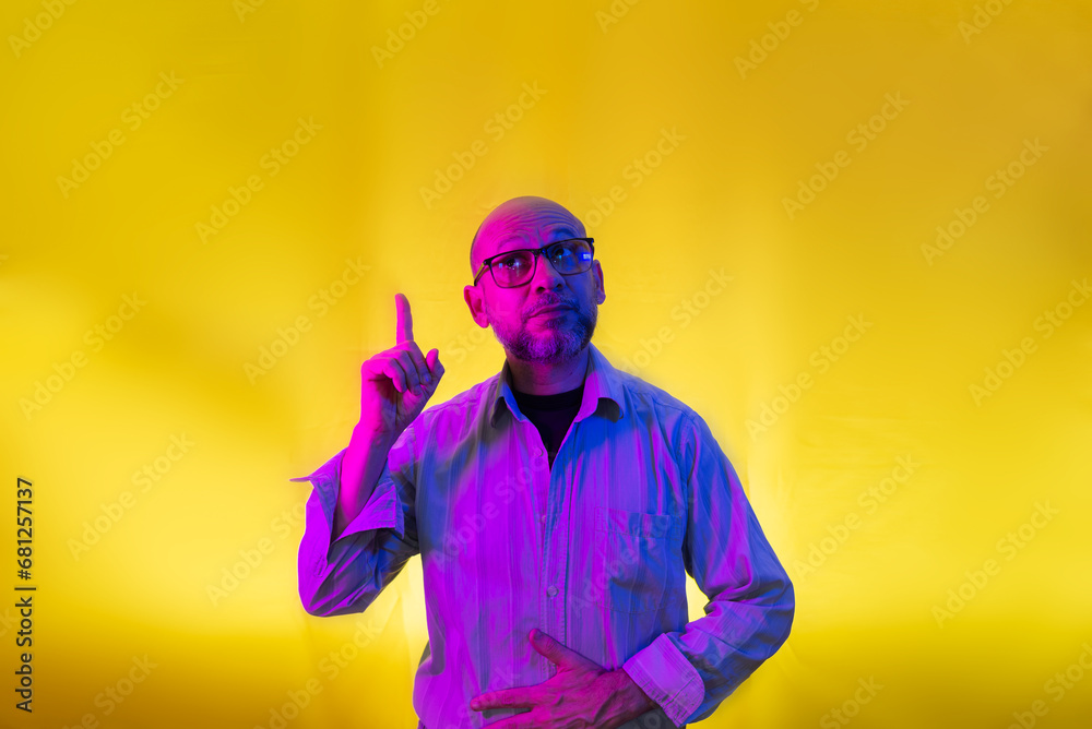 Bald, bearded man wearing glasses pointing up. Bald, bearded man wearing glasses pointing up.