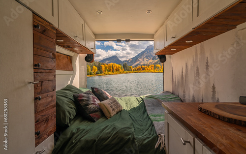 Vanlife Campervan Bed in Wilderness Colorado Mountain Aspen Tree Lake in Autumn Fall Foliage. Green Bedding and Wooden Details with Back Door Open.. photo