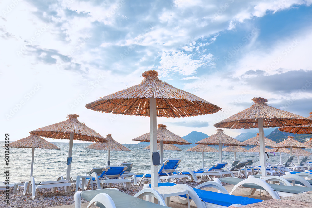 Fototapeta premium Beach umbrellas and sunbeds on the background of the sea . Golden Hours by the Sea