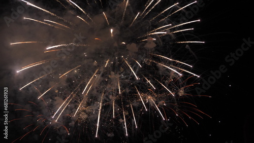 Fireworks sparkling flowers blasts with smoke cloud in black night sky