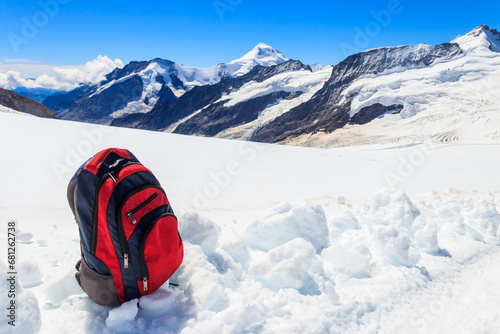 Tourist backpack on a snow on background of mountains in Swiss Alps. Travel outdoor concept
