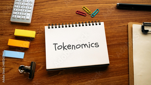 There is notebook with the word Tokenomics. It is an abbreviation for Tokenomics as eye-catching image.