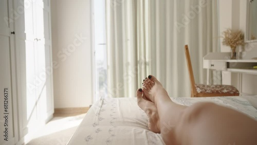 Bright and Sunny Bedroom, First-person View of a Woman's Legs Being Caressed by a Man's Hand, Slowly Revealing Them. Concept of Romantic Relationships. photo