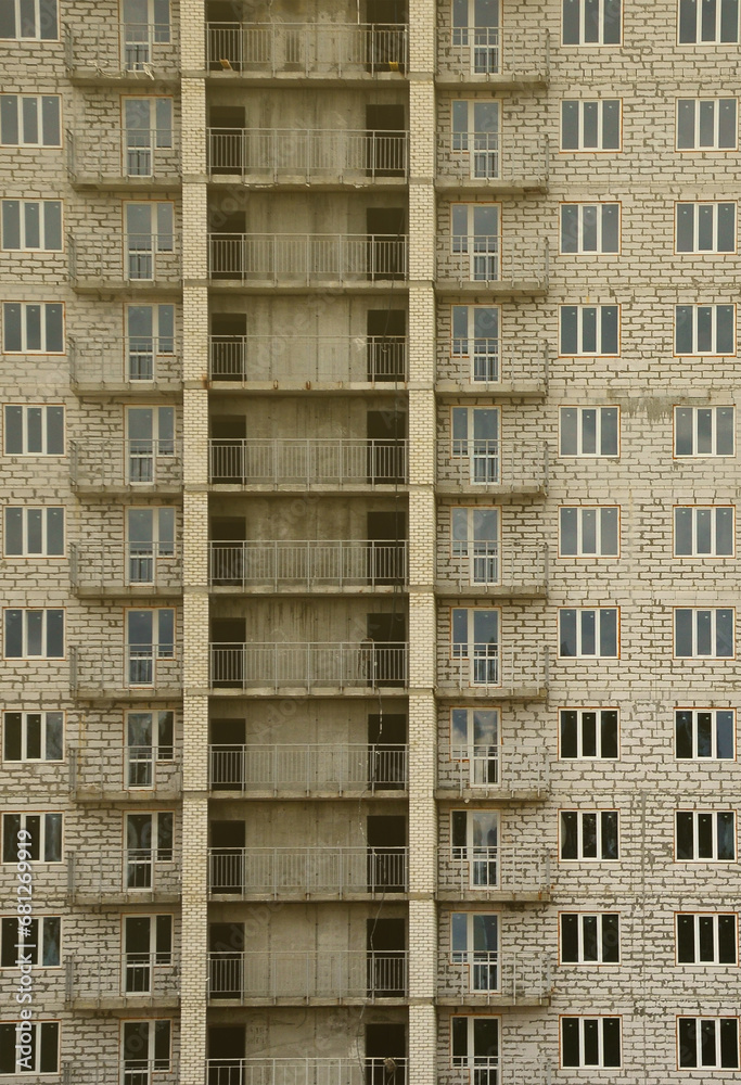 Textured pattern of a russian whitestone residential house building wall with many windows and balcony under construction