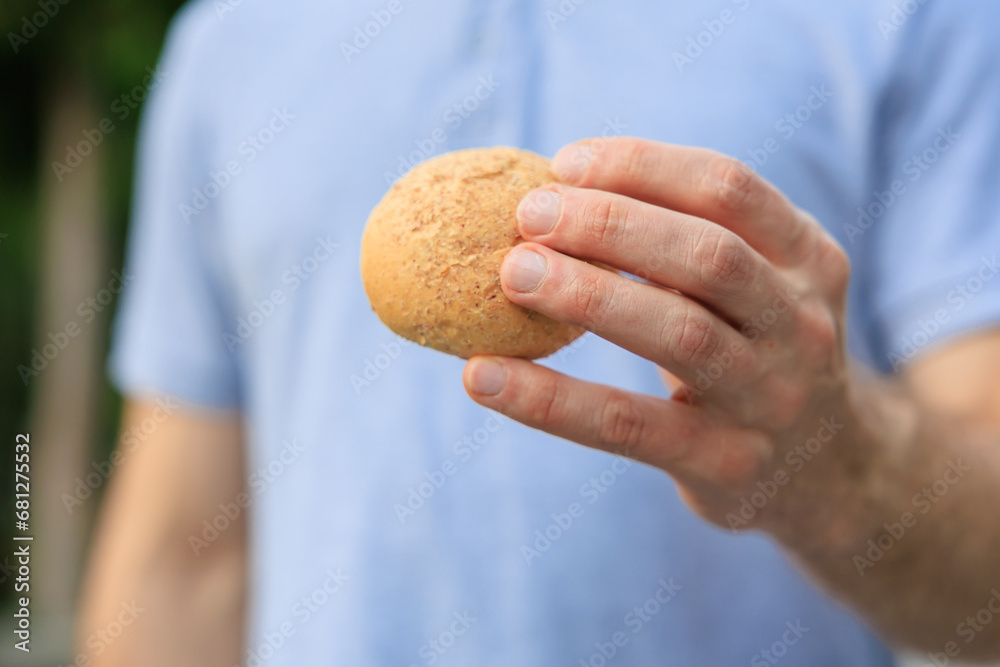 Man's hand holds mini bread, snack and fast food concept. Selective focus on hands with blurred background Man's hand holds mini bread, snack and fast food concept. Selective focus on hands with blurred background