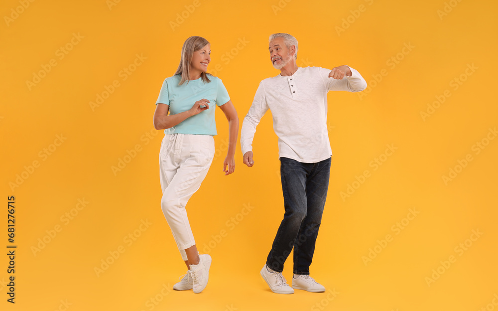 Senior couple dancing together on orange background