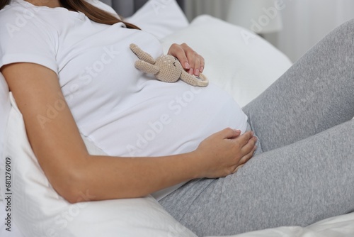 Pregnant woman with bunny toy lying on bed, closeup