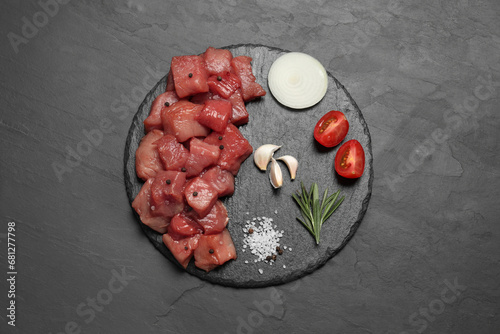 Raw beef meat and different ingredients for cooking delicious goulash on black table, top view