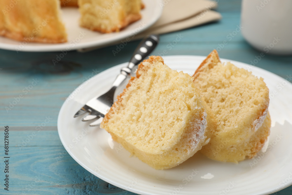 Pieces of delicious sponge cake and fork on light blue wooden table, closeup