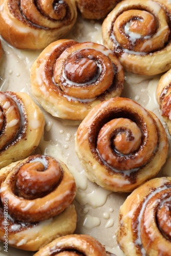Tasty cinnamon rolls with cream on parchment paper, above view