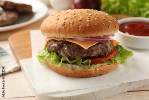 Tasty hamburger with patty, cheese and vegetables on light table, closeup
