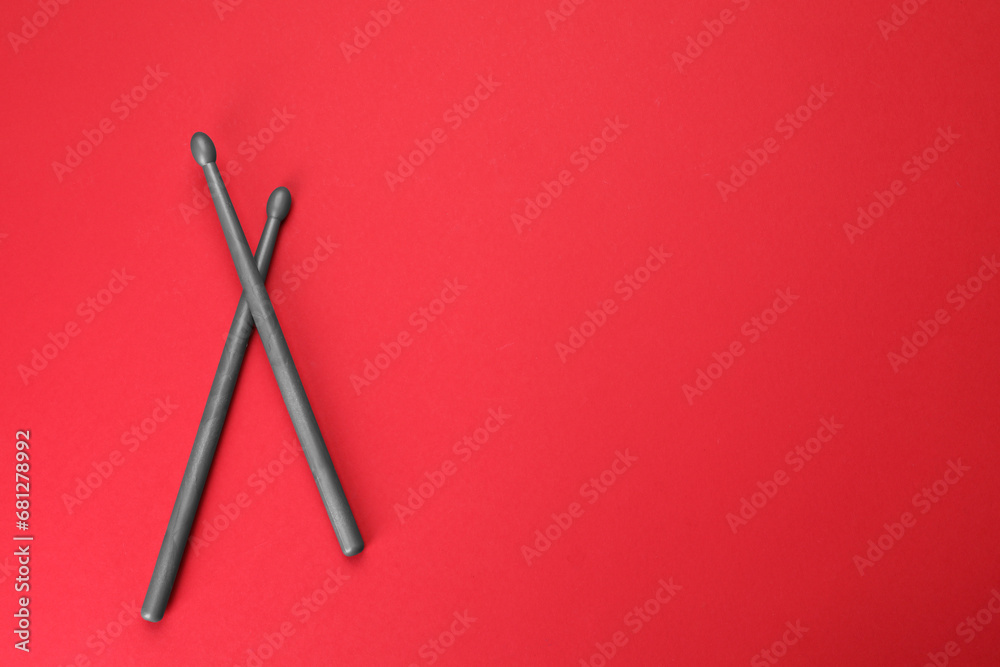 Two gray drum sticks on red background, top view. Space for text Two gray drum sticks on red background, top view. Space for text