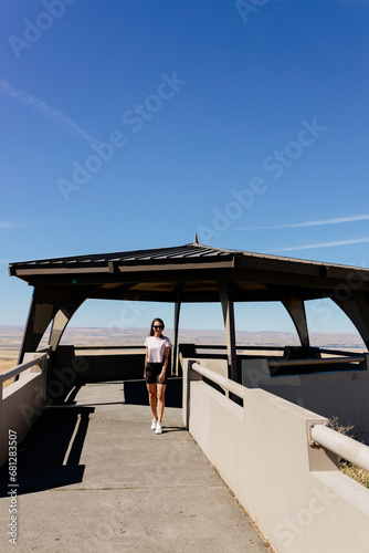 A young slender girl in short shorts and a nasty pink T-shirt with long dark hair walks among a beautiful recreation area. Scenic point view in Pendleton, Oregon, USA photo