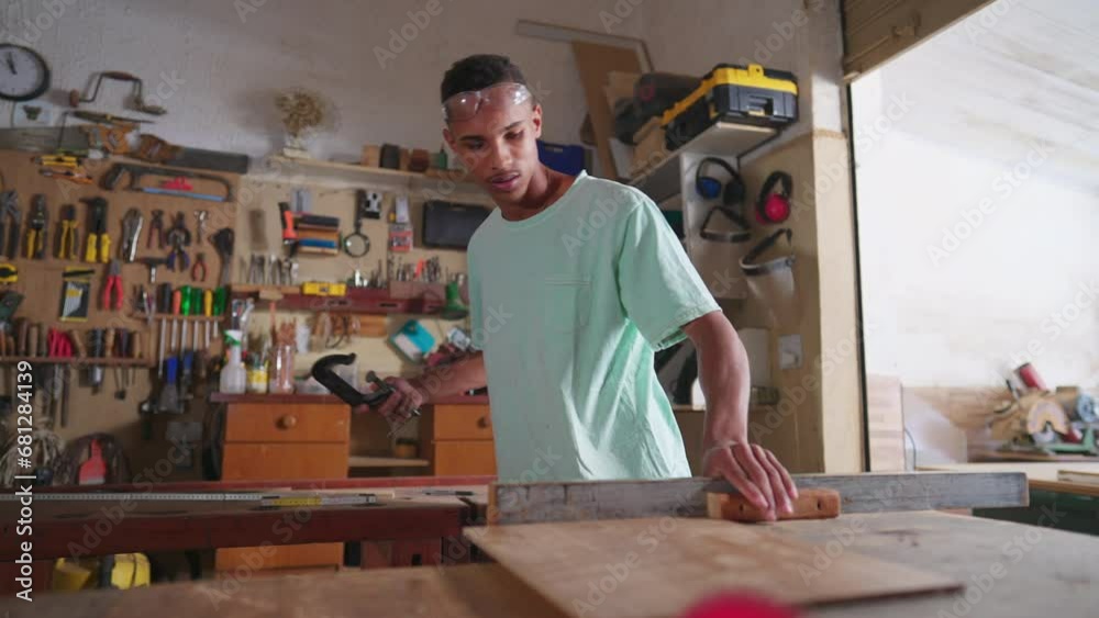 One Focused Black Brazilian Carpenter sawing Wood in Workshop. Young apprentice working at carpentry business One Focused Black Brazilian Carpenter sawing Wood in Workshop. Young apprentice working at carpentry business