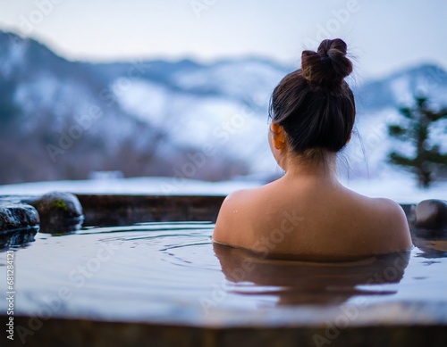  雪景色のきれいな温泉に浸かっている日本人女性の後ろ姿 