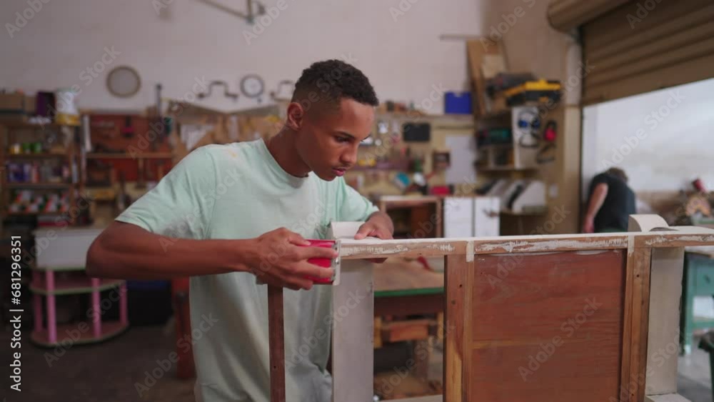 One young black carpenter polishing wooden furniture standing inside carpentry workshop. Concentrated worker repairing and creating handmade object One young black carpenter polishing wooden furniture standing inside carpentry workshop. Concentrated worker repairing and creating handmade object