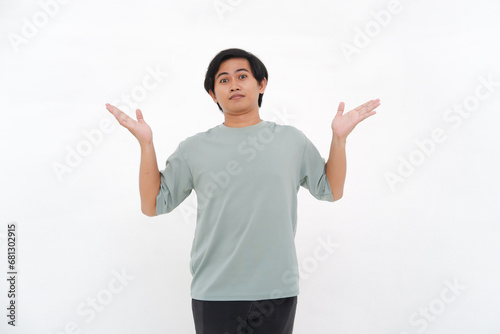 A young Asian man raises his hand with a confused and clueless expression photo