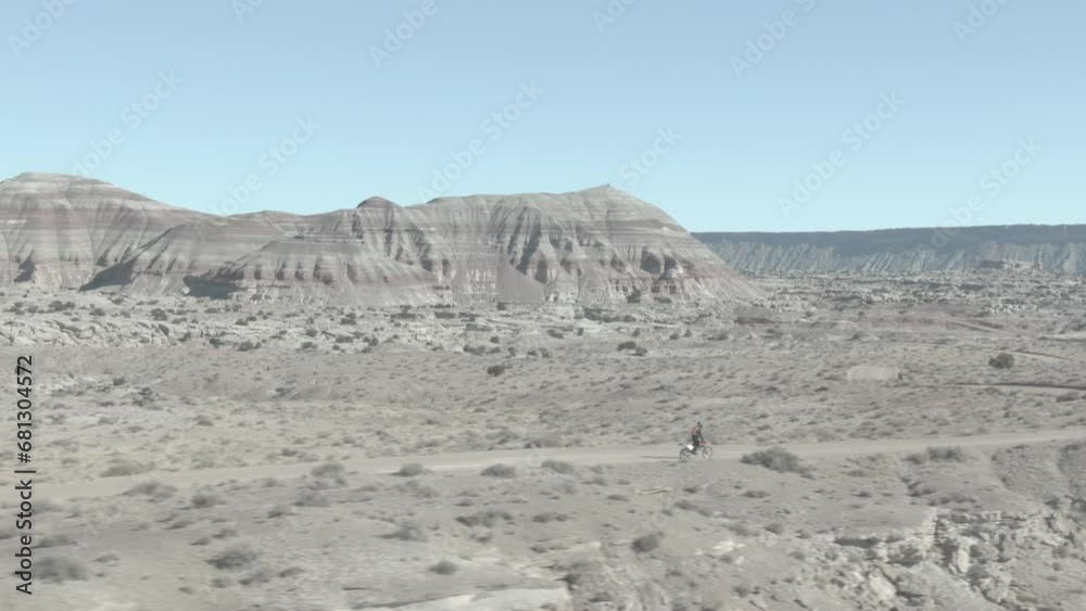 Aerial of Dirt biker on dirt road in Cathedral Valley in central Utah in flat color Aerial of Dirt biker on dirt road in Cathedral Valley in central Utah in flat color