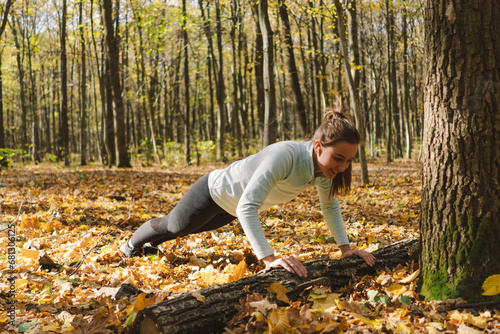 Beautiful girl doing fitness in nature on a sunny autumn forest. Body positive, sports for women, harmony, healthy lifestyle, self-love and wellness.