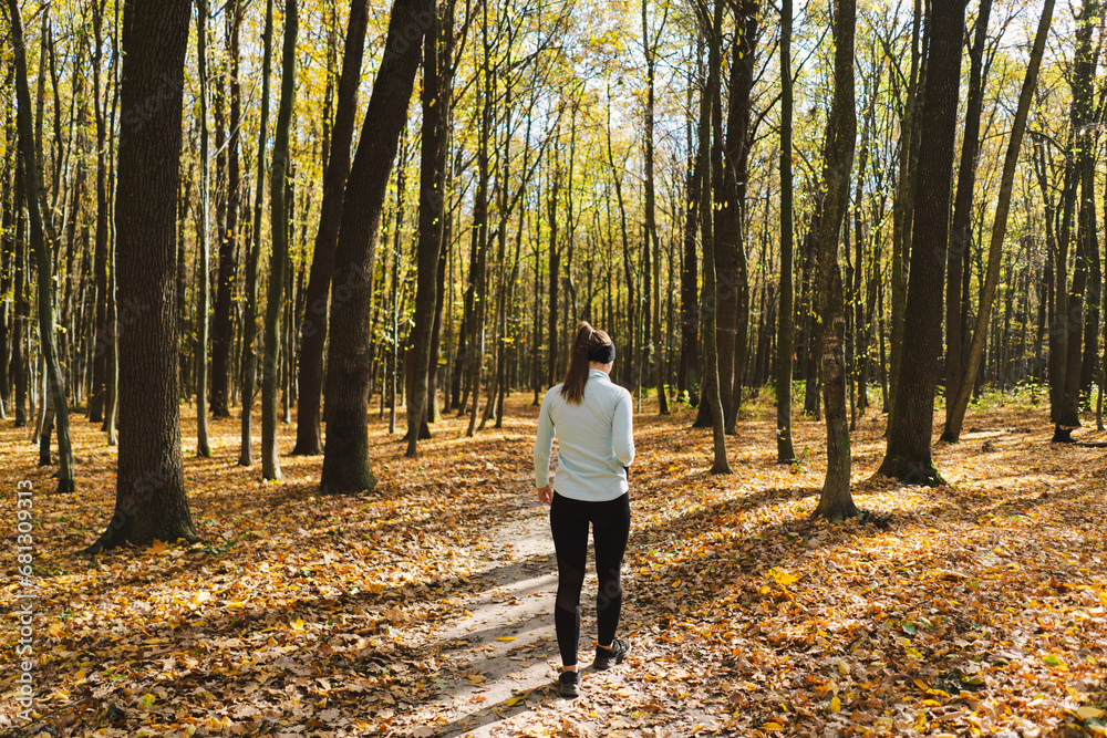 Fototapeta premium Beautiful girl doing fitness in nature on a sunny autumn forest. Body positive, sports for women, harmony, healthy lifestyle, self-love and wellness.