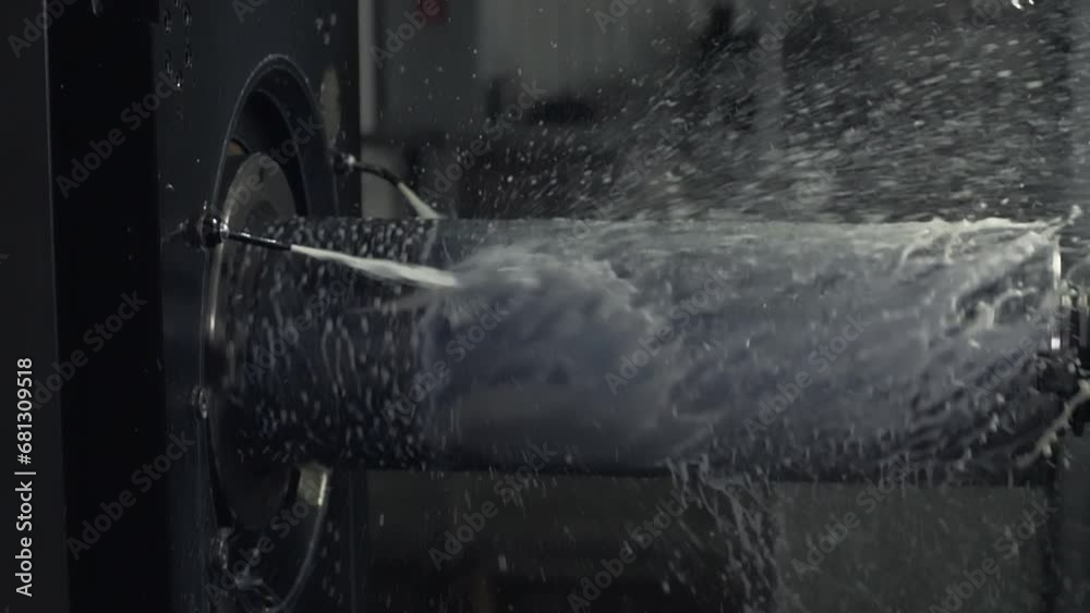 Automated machinery is operating at industrial metalworking plant. Automated metalwork milling machine cooled down by water. Shaft of automated metalwork cutter machine is rotating. Metal production