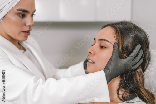 Specialist stretching and observing the skin of a patient's face photo