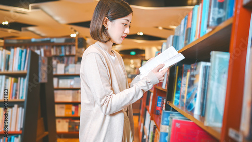 Portrait of young adult southeast asian woman reading book at bookstore shop photo