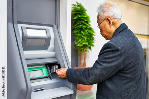 銀行のATMの操作をしようとする高齢者の男性 photo