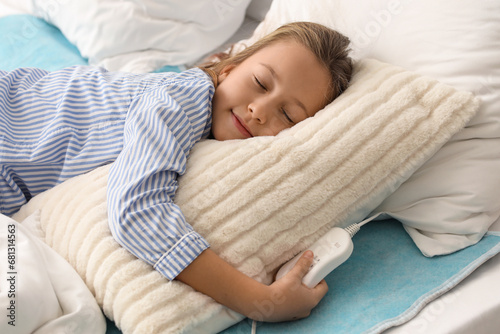 Little girl sleeping on electric heating pad in bedroom photo