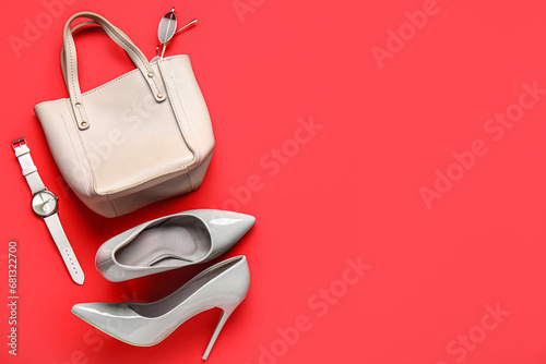 Composition with stylish female shoes, handbag and wristwatch on red background