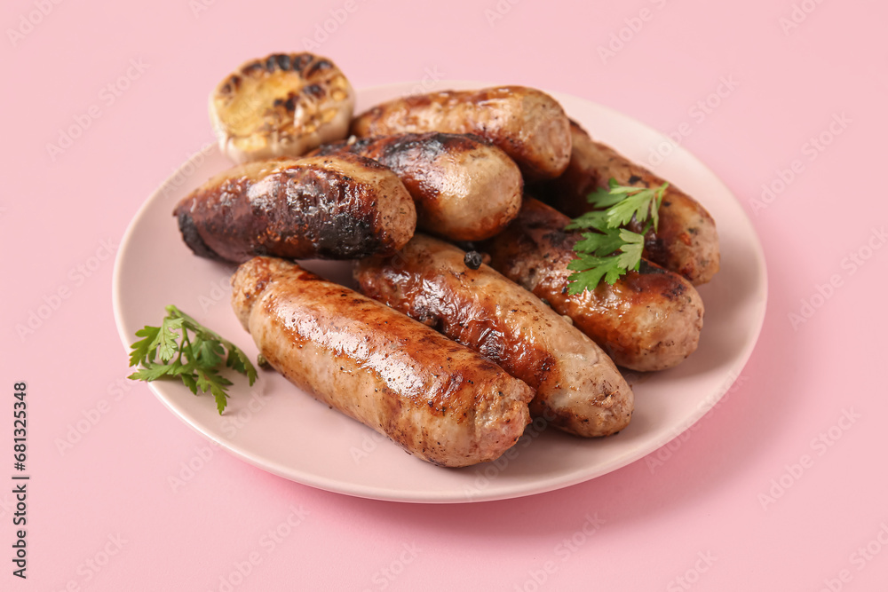 Plate of tasty grilled sausages on pink background